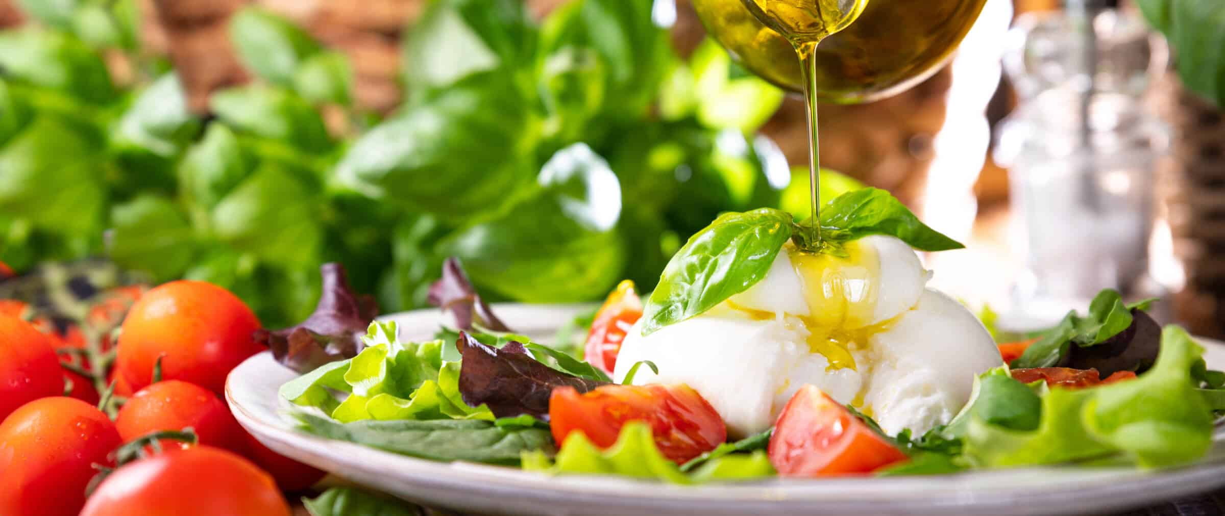 Salad with Tomatoes, Burrata, basil,olive oil. middle name Burratina. Traditional cheese from the south of Italy in the Puglia region. Round soft cheese inside liquid stracciatella texture.